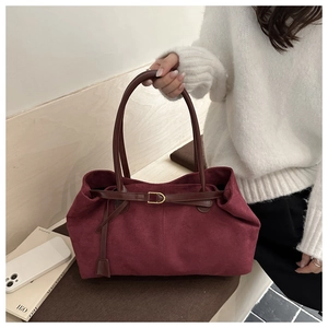 Macro shot of burgundy faux suede tote bag featuring a gold D-ring and brown slim handles