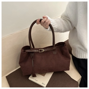 Macro view of dark brown suede tote bag featuring fine leather straps and metal buckle