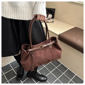 Detail of dark brown suede tote bag featuring a gold buckle and slim handle straps