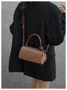 Detail of vintage brown leather handbag with unique knotted handle and gold metal clasp