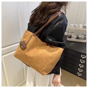 Detail of tan suede tote bag featuring its soft texture and long shoulder strap