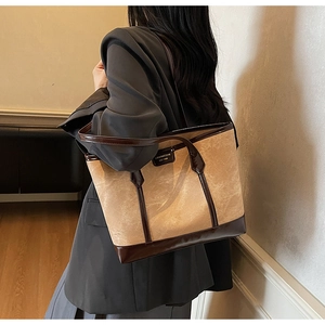 Detail of retro color-block tote bag with vintage metal logo plaque and brown straps