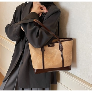 Close-up of the vintage suede tote bag showing the branded nameplate and refined stitching