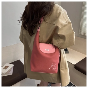 Dettaglio borsa tote rosa corallo con illustrazione di cane e fibbia a forma di osso