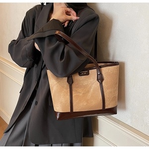 Detail of vintage beige textured tote bag with dark brown patent leather straps and gold logo