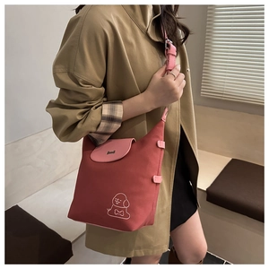 Dettaglio della borsa tote in tela rossa con patta rosa e motivo a cane indossata dal modello