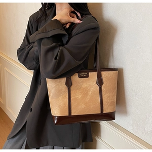 Side view of a large khaki contrast tote bag with brown straps worn on a model shoulder