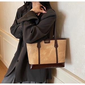 Brown vintage suede tote bag with brand logo shown on a model in a grey blazer