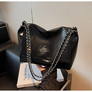 Detail of glossy wrinkled leather tote with silver chain strap and embossed logo