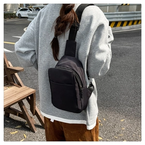 Detail of black crossbody chest bag with adjustable strap worn on urban street