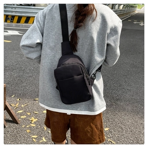Modern black nylon chest bag for commuting and travel shown on back in urban street setting