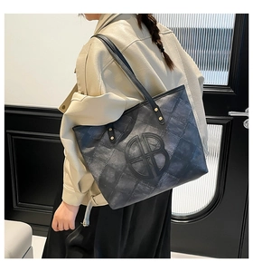 Close-up of a large grey tote bag featuring quilted texture and a round B logo detail