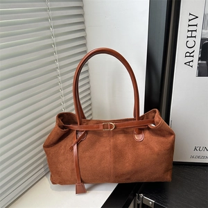 Caramel suede tote bag with leather handles and gold buckle in a minimalist home setting