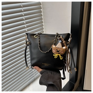 Close-up of black leather tote bag with metal chain handle and cute bear charm detail