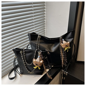 Detail of black leather chain bags with golden text and cute bear plush charms