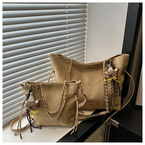 Detail of khaki suede tote bags with chain straps and cute bear charms in natural light