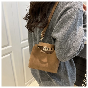 On-body view showing the adjustable shoulder strap and gold clasp of the brown suede bag