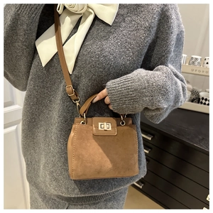 Detailed view of brown crossbody bag with matte finish and metal twist lock closure