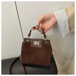 Detail of coffee brown suede tote bag featuring gold square twist lock and smooth leather