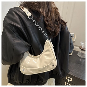 Close-up of off-white hobo bag showing glossy PU leather and silver rivet details