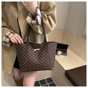 Close-up of deep brown tote bag with M-letter prints and golden metal plate detail