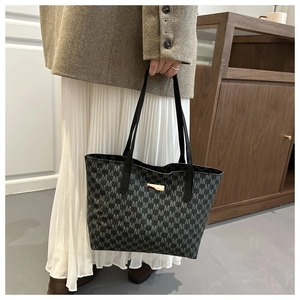 Detail of vintage black tote bag with gray letter M pattern and gold metal hardware