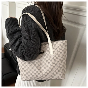 Close-up of a large tote bag with M letter monogram print worn on the shoulder