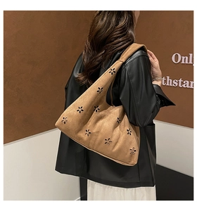 Close-up of laser-cut floral hollow patterns on brown suede shoulder bag material