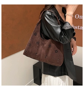Close-up of laser-cut petal patterns on dark brown suede shoulder tote bag with model