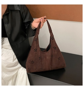 Detail of dark brown suede tote bag featuring artistic hollowed-out floral pattern designs