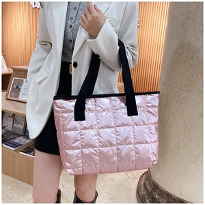 Détail du sac cabas matelassé rose avec anses noires dans un décor intérieur doux