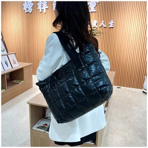 Détail du sac cabas noir brillant matelassé avec motif à carreaux et large bandoulière