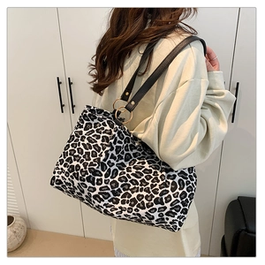 Detail of a zebra print tote bag with black leather straps and gold ring hardware