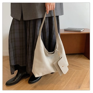 Detail of beige suede tote bag with matching pouch shown in a cozy interior setting
