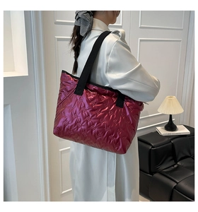 Fuchsia quilted tote bag detail with letter embossing and wide black shoulder strap