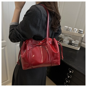 Detail einer roten Lackleder-Schultertasche mit stilvoller Schleife und Tunnelzugverschluss
