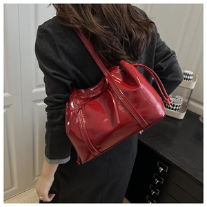 Macro shot of red glossy patent leather tote bag with drawstring detail on a shoulder