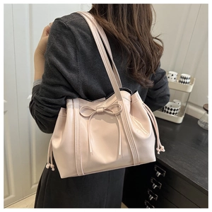 Close-up of pink tote bag with bow detail and glossy leather texture on a shoulder