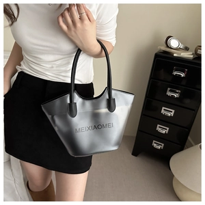 Detail of translucent grey bucket bag with black handles held by model in modern home