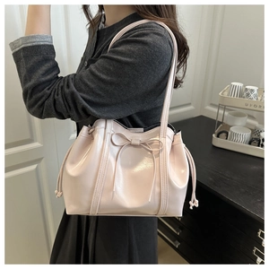 Detail der hellrosa Lackleder-Schultertasche mit dekorativer Schleife und Tunnelzug an der Seite