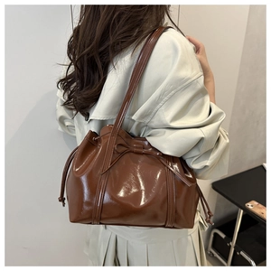 Detailed view of the brown patent leather texture and bow design on the shoulder bag