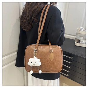 Detail view of brown vintage leather bowling bag with cute plush cloud charm for women