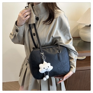 Detail of black leather bowling bag with cute white cloud plush charm and silver buckle