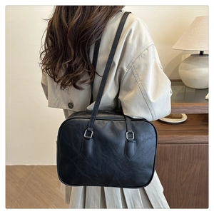 Detail of black vintage leather handbag with slender straps and silver metallic buckles