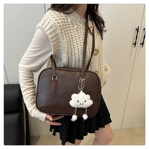 Detail of vintage brown PU leather bowling bag with cute white plush cloud charm accessory