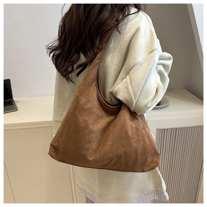 Close-up of soft brown faux suede hobo bag carried by model in casual minimalist outfit