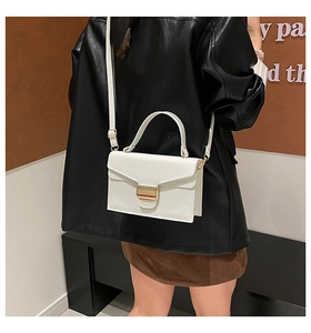Sac bandoulière blanc grainé avec boucle dorée porté par un mannequin pour l'échelle