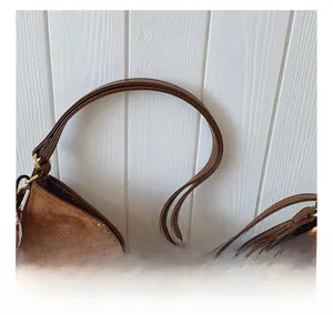 Detail of brown suede tote with smooth leather strap and gold buckle hardware