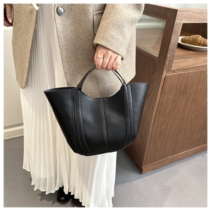 Détail d'un sac seau en cuir noir avec bord incurvé et triple couture verticale