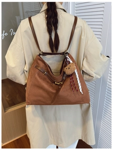 Brown faux suede tote bag with brown leather straps and cute bear charm worn by a model